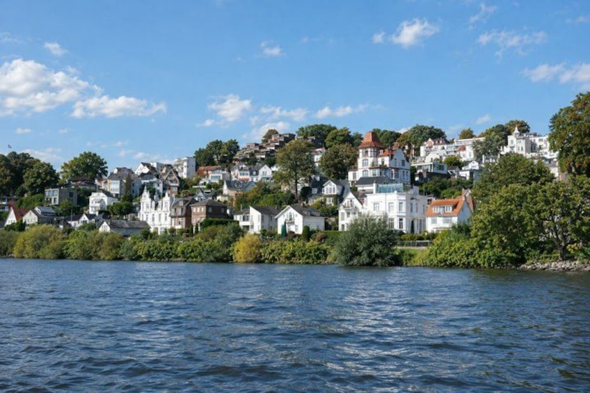 A coastal town with white houses, a river, and greenery. 5