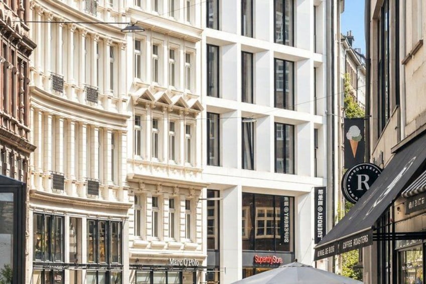A street with a white building, a Marc by Oscar de La Renta store, and a Superdry store. 2