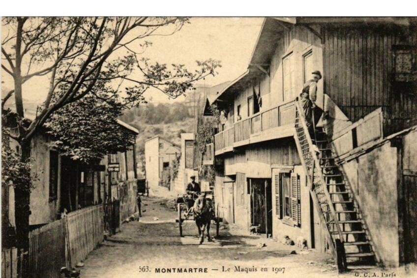 A narrow street in Montmartre with buildings, a staircase, and a horse-drawn carriage. 3