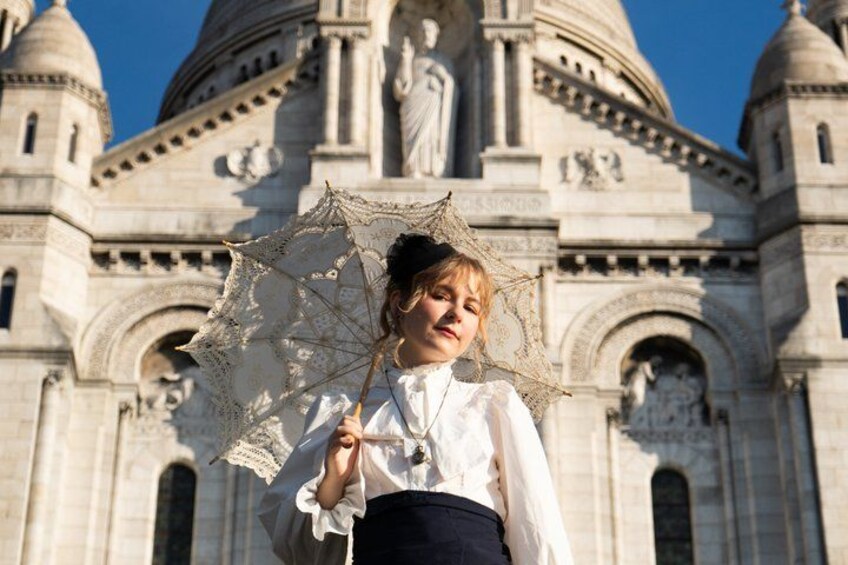 A person holding an umbrella in front of a large, ornate building with domes and statues. 1