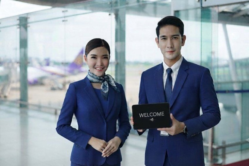 Two individuals in blue uniforms holding a welcome sign in an airport terminal. 3