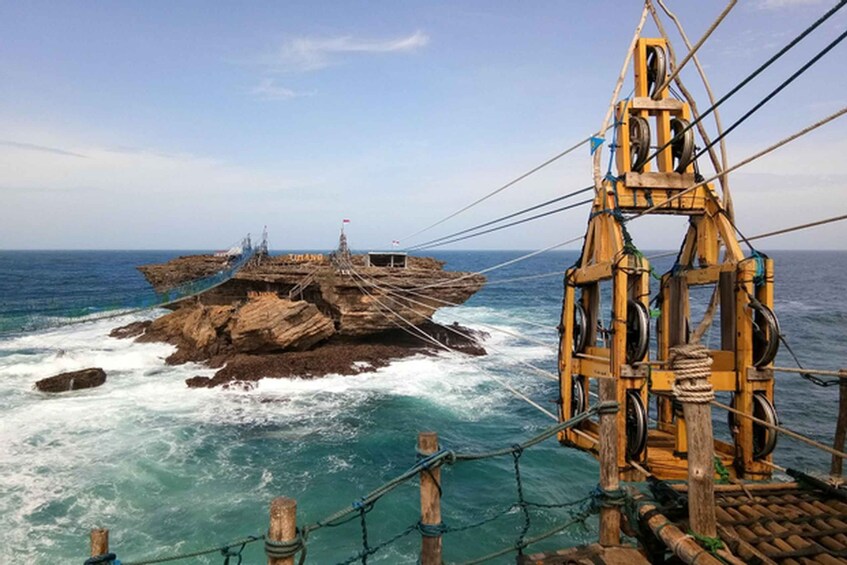 A rocky island with a flag, surrounded by rough sea. 4