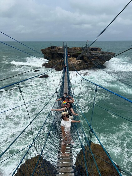 A rope bridge over a rocky coastline with rough sea waves. 3
