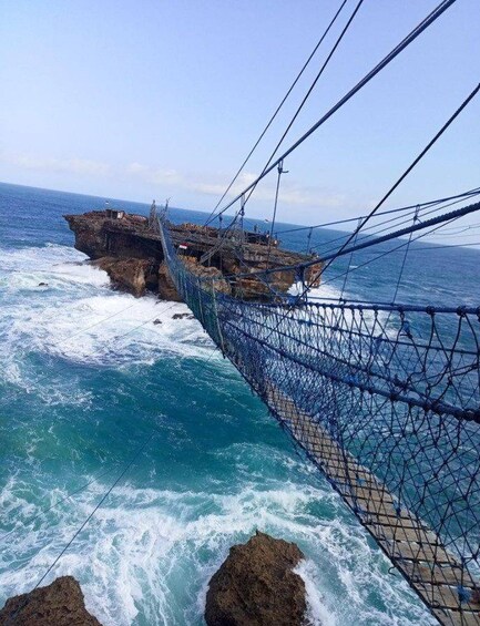 A suspension bridge over a rocky coastline with waves crashing against the rocks. 5