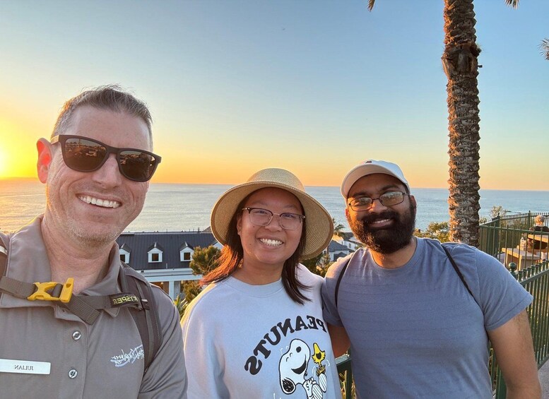 Three people standing on a beach with a sunset in the background. 5