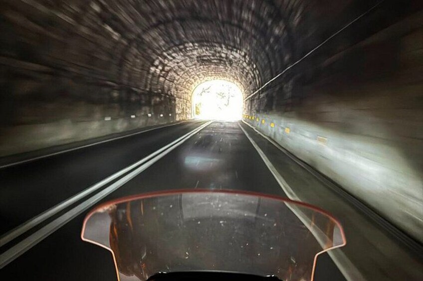 A tunnel with a vehicle in the foreground and a bright exit at the end. 5