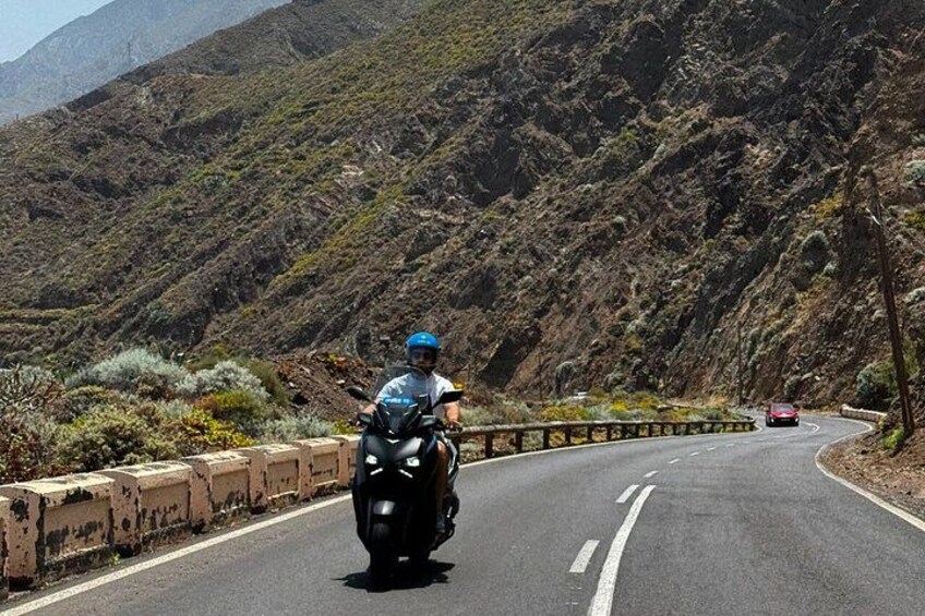 A motorcyclist on a winding mountain road with rocky terrain and sparse vegetation. 4