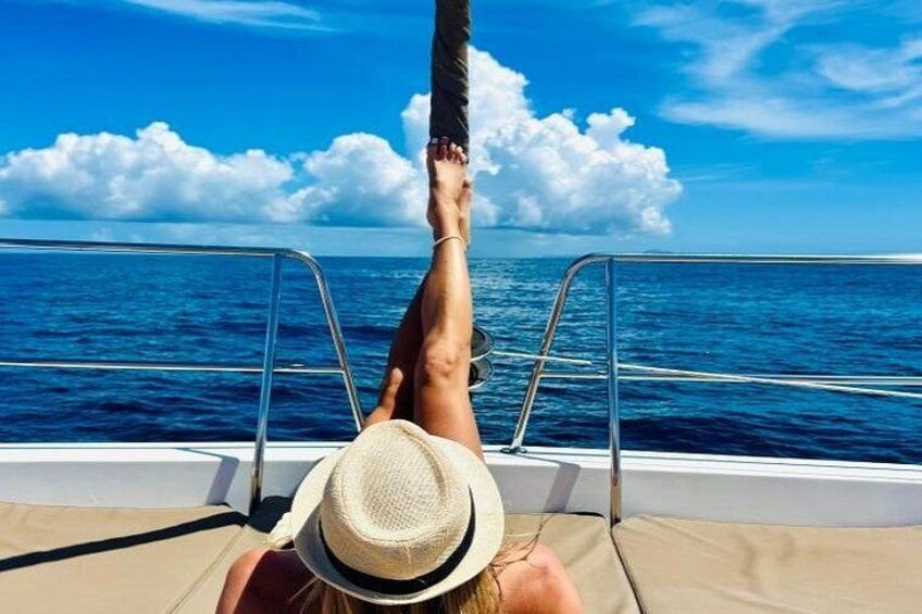 A person relaxing on a boat with a straw hat, facing the ocean. 4