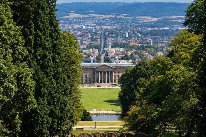 A large building with columns, surrounded by trees and a view of a cityscape. 3