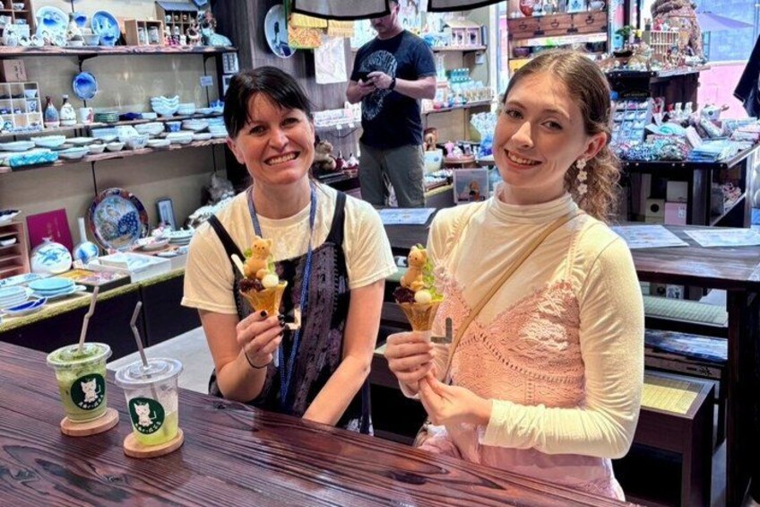 Two people holding ice cream cones at a counter with various items in the background. 5