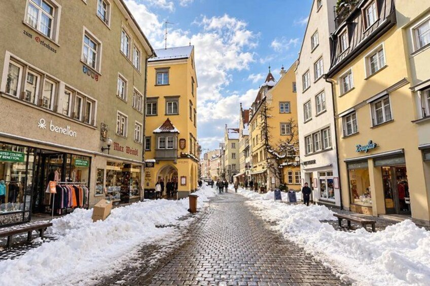 A cobblestone street lined with buildings, some with snow on the ground. 3