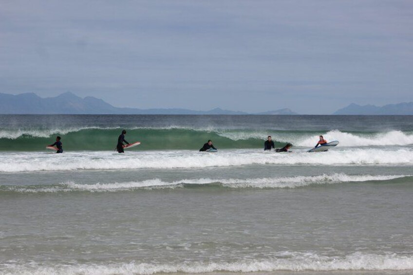 Surfers waiting for waves, ocean, and distant mountains. 4
