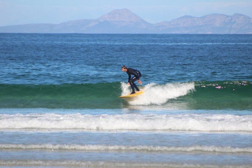 A person surfing on a wave with mountains in the background. 3