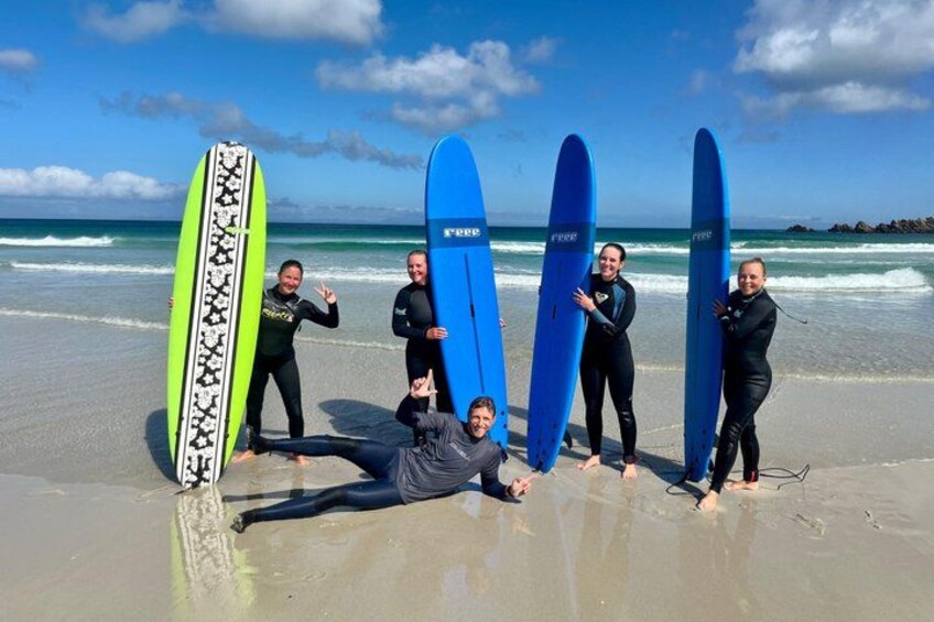 A group of people on a beach holding surfboards. 1