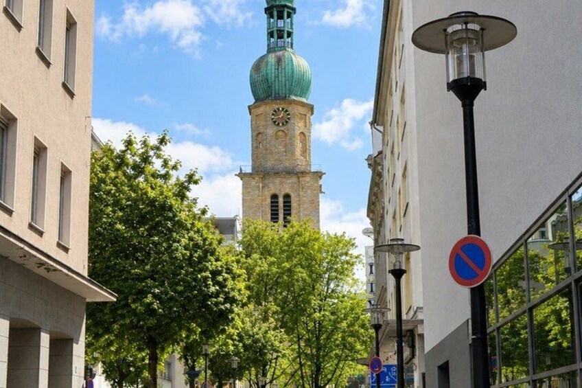 A historic tower with a clock, surrounded by modern buildings and trees. 3