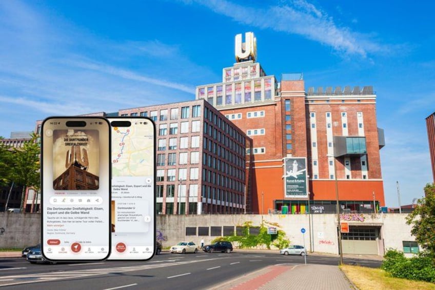 A modern building with a large 'U' on top, a red brick facade, and a clear blue sky. 1