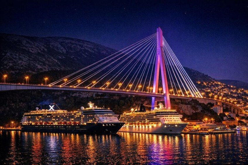 A cable-stayed bridge at night with two cruise ships docked nearby. 3