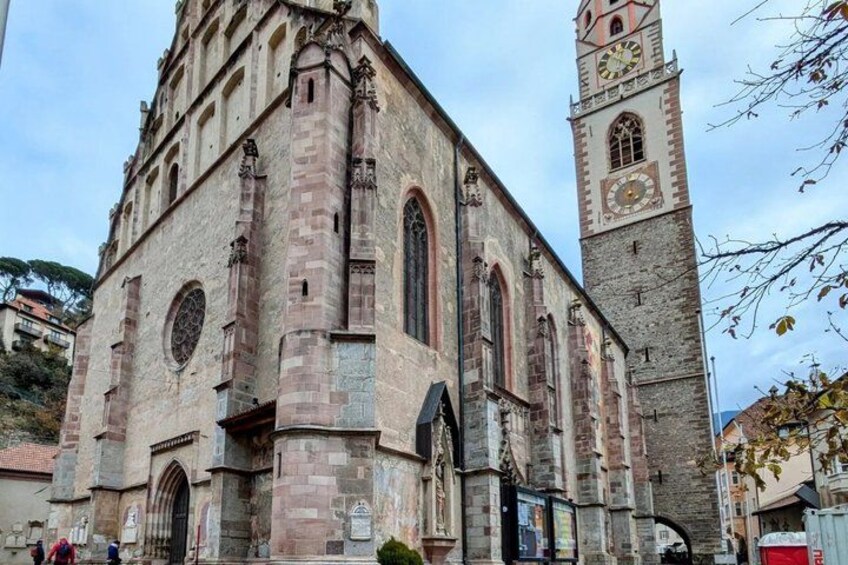 A historic church with a tall clock tower, arched windows, and a stone facade. 5