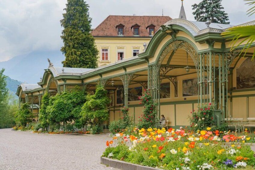 A historic building with ornate architecture, a cobblestone courtyard, and a vibrant flower garden. 3