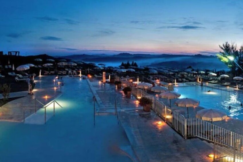 A swimming pool area with lounge chairs and umbrellas, surrounded by a fence and overlooking a mountainous landscape. 3