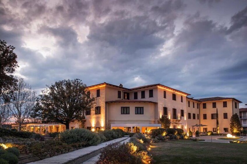 A multi-story building with illuminated windows, surrounded by a well-maintained garden and pathway. 4