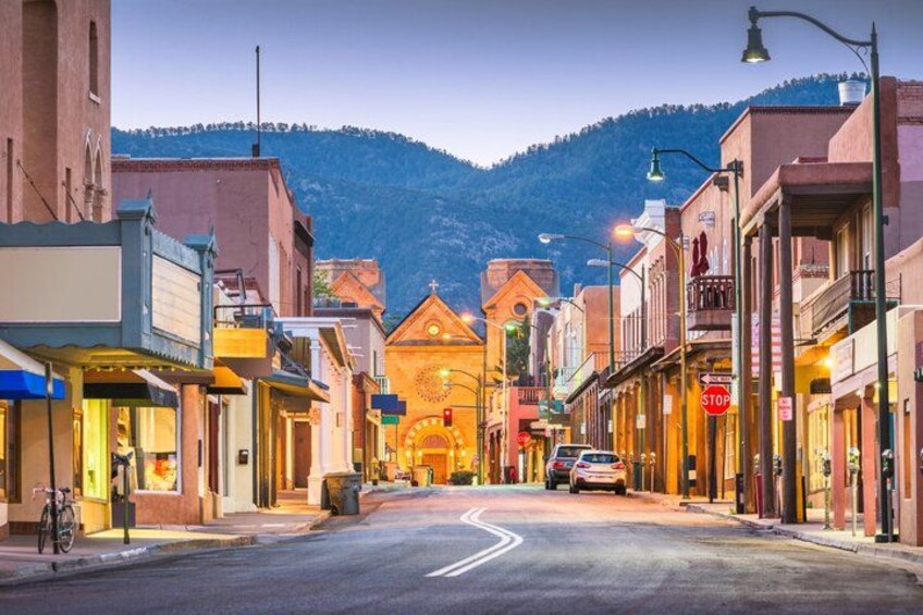 A street lined with buildings, a stop sign, and a mountain in the background. 2