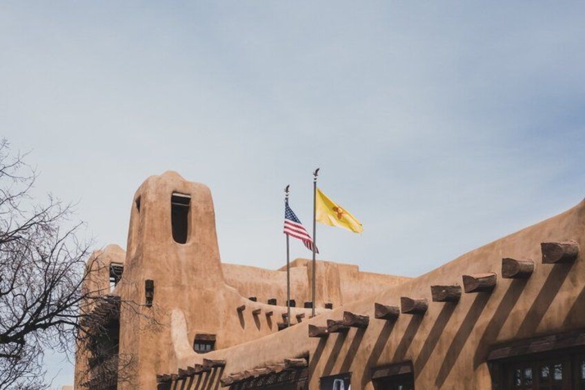 A building with a unique architectural style, featuring a large central tower and a flagpole with two flags. 5