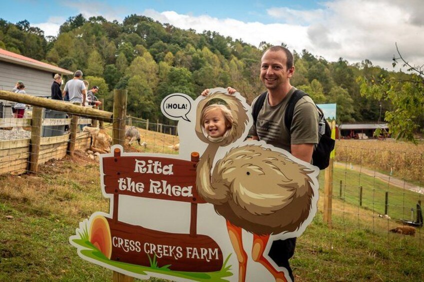A man and a child at a farm with a sign that reads 'Rita the Rhea' and 'Cress Creek Farm.' 5