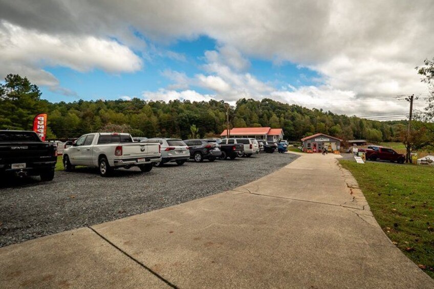 A parking lot with several pickup trucks and a gravel path leading to a building with a red roof. 3