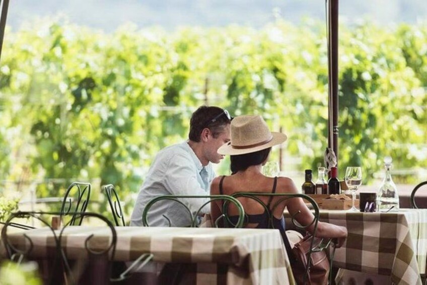 A couple dining outdoors with a vineyard in the background. 3