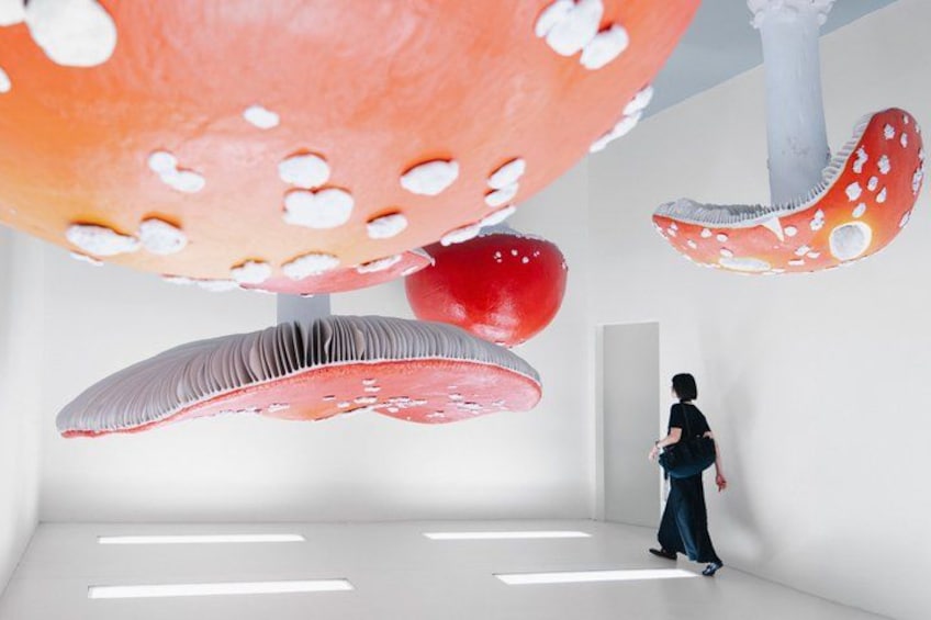 A person in a white room with large mushroom-shaped sculptures. 1