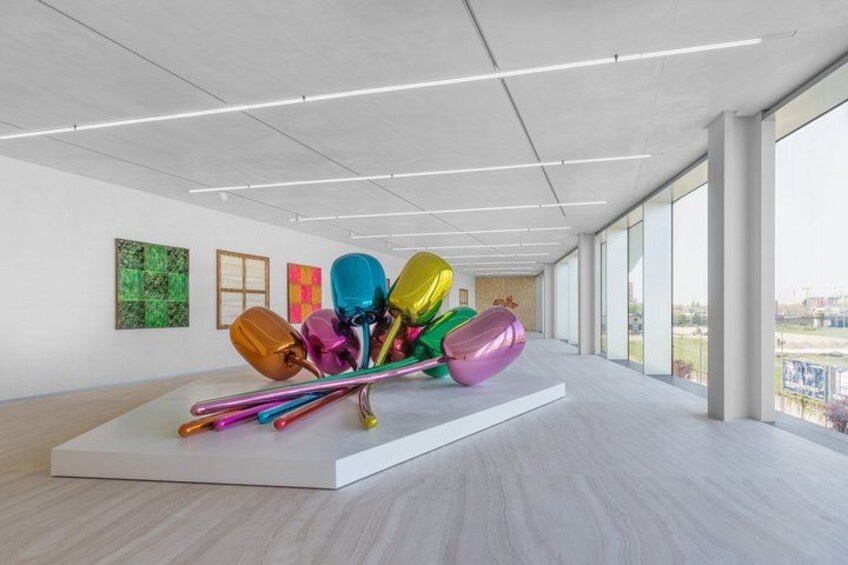 A modern art gallery with a sculpture of colorful metallic objects on display. 5