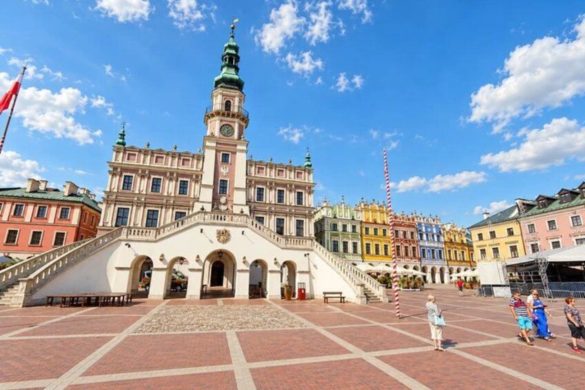 A historic building with a clock tower, a red flag, and a red and white striped pole. 3