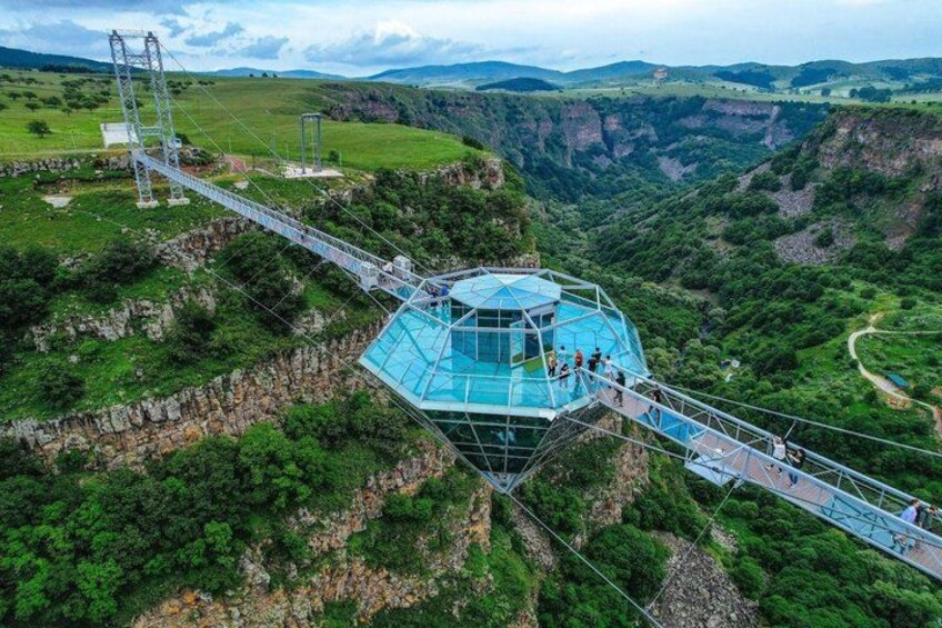 A glass bridge over a canyon with a glasshouse structure at the end. 1