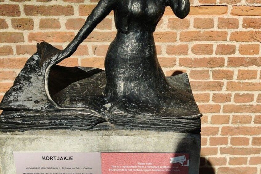 A sculpture of a woman with a fish, placed on a brick wall. 3