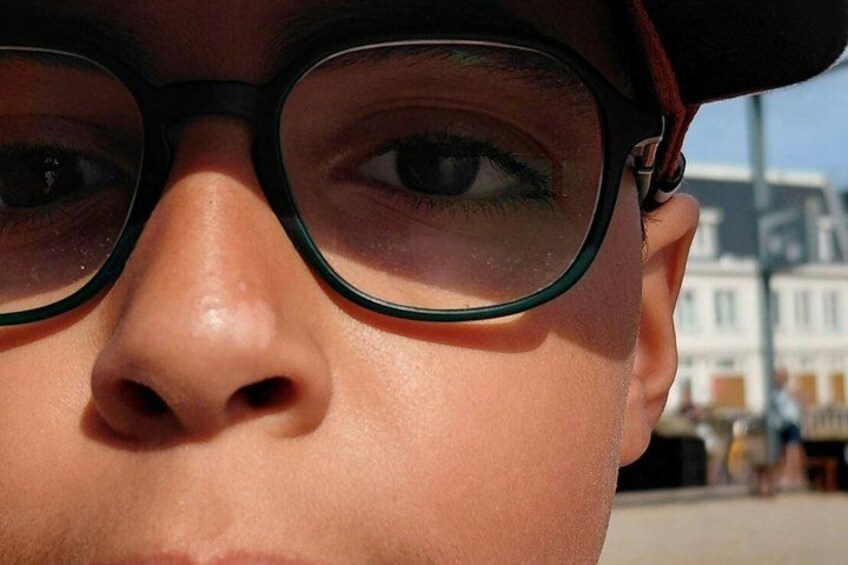 A close-up of a person's face with glasses, a cap, and a blurred background. 2