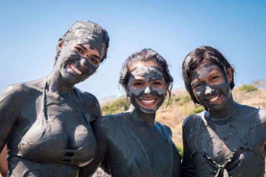 Three people covered in mud, standing outdoors. 4