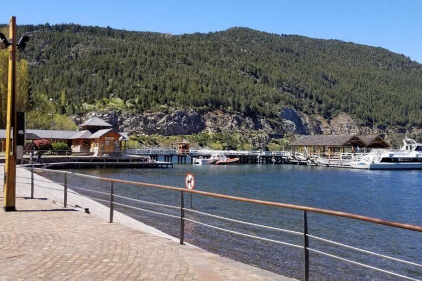 A waterfront with a dock, a boat, and a mountain in the background. 3