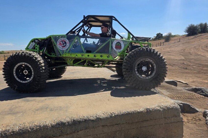 A green off-road vehicle on a dirt path. 2