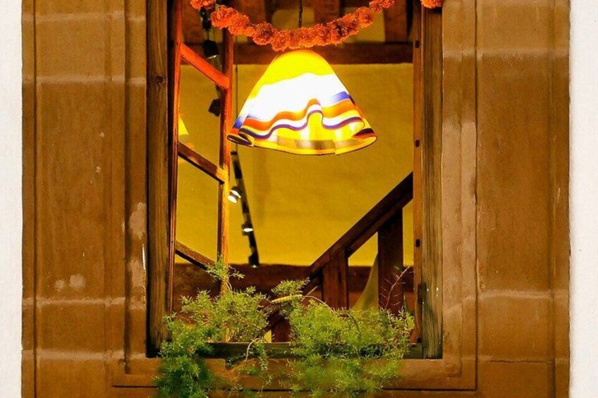 A window with a colorful lamp, wooden shutters, and a small plant. 5