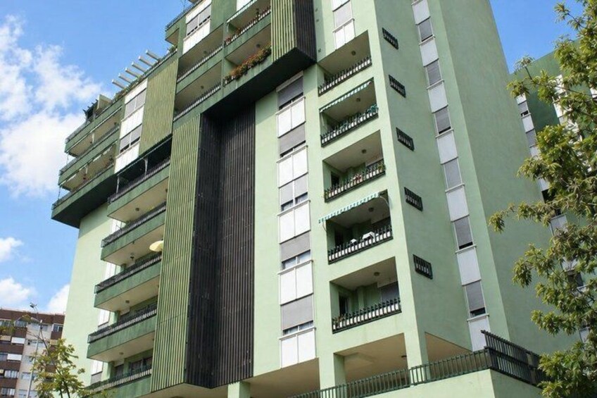 A multi-story building with balconies and a central vertical feature. 2
