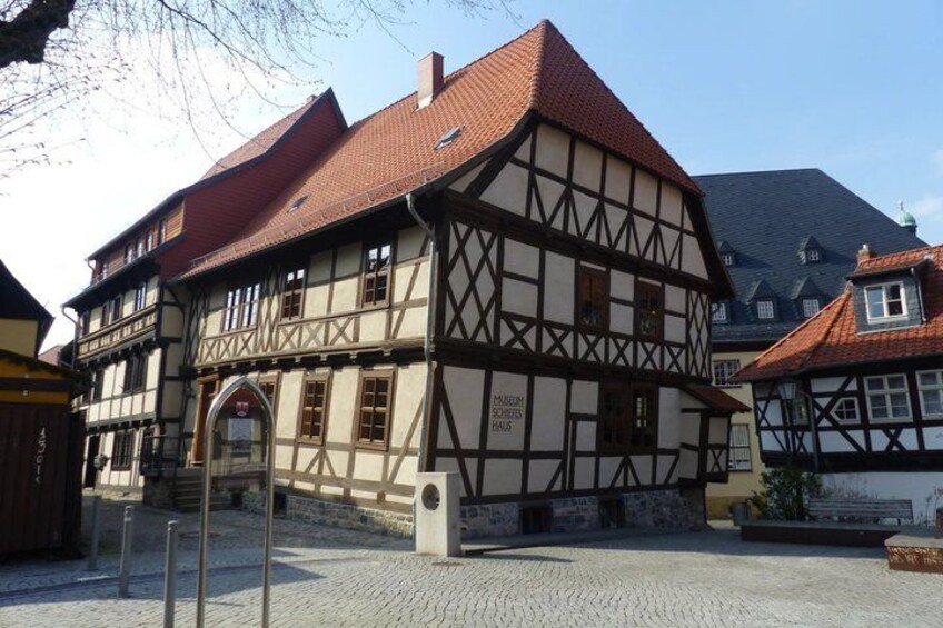 A traditional half-timbered building with a red-tiled roof and a cobblestone street. 5
