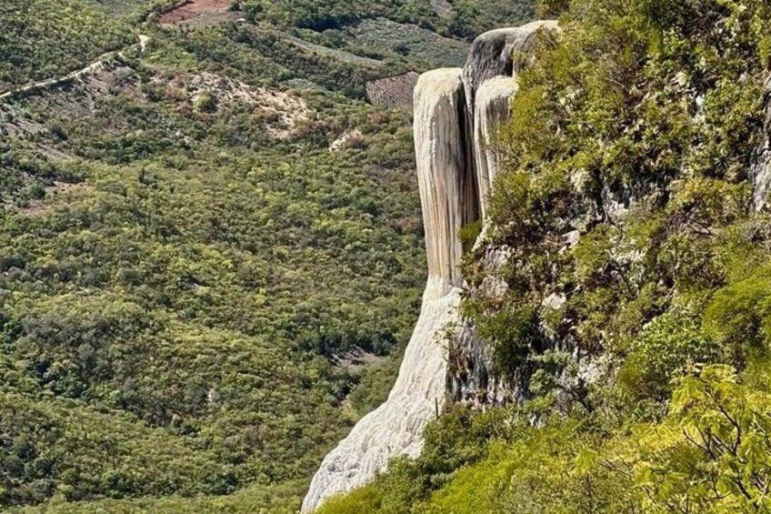 A waterfall cascading down a steep cliff surrounded by dense greenery. 5