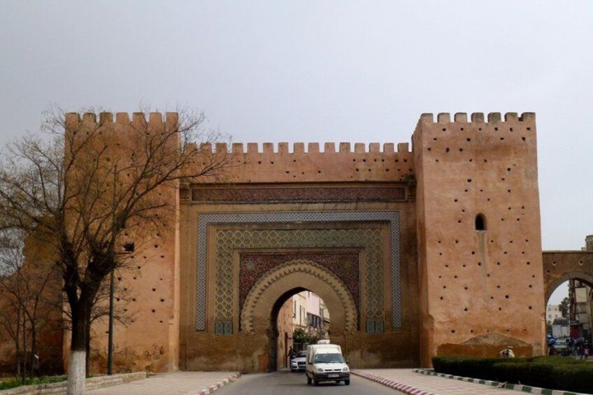 A large, ornate gate with intricate designs and a vehicle passing through it. 5