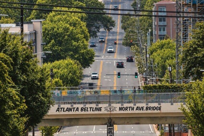 A multi-lane road with vehicles, a pedestrian bridge, and trees. 3