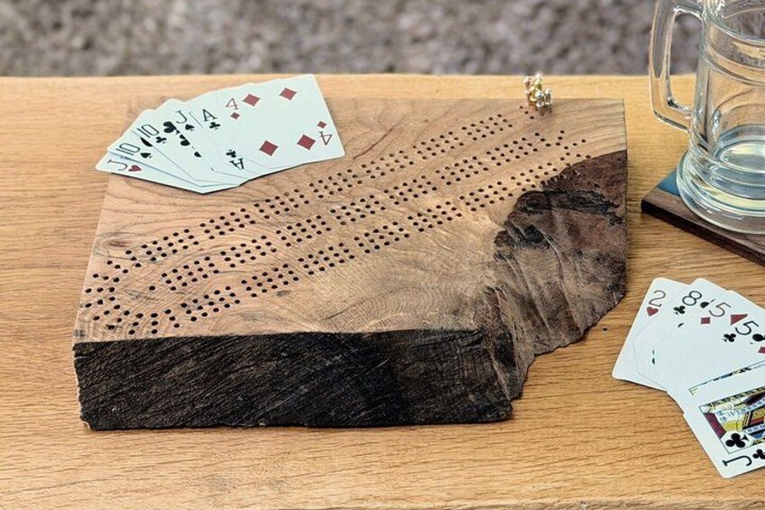 A wooden board with playing cards and a glass mug on a wooden table. 3