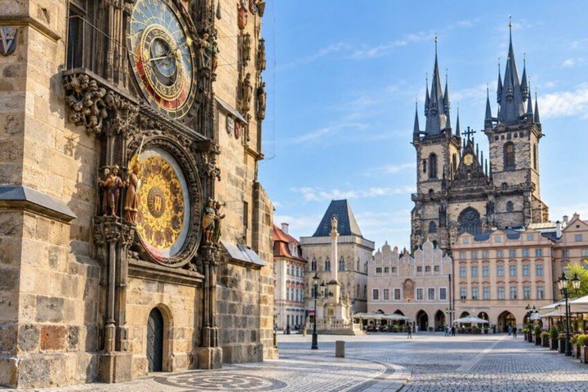 A historic building with ornate clocks and a prominent church with spires in the background. 3