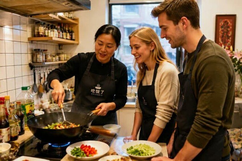 A person cooking in a kitchen with a wok, surrounded by other people. 4