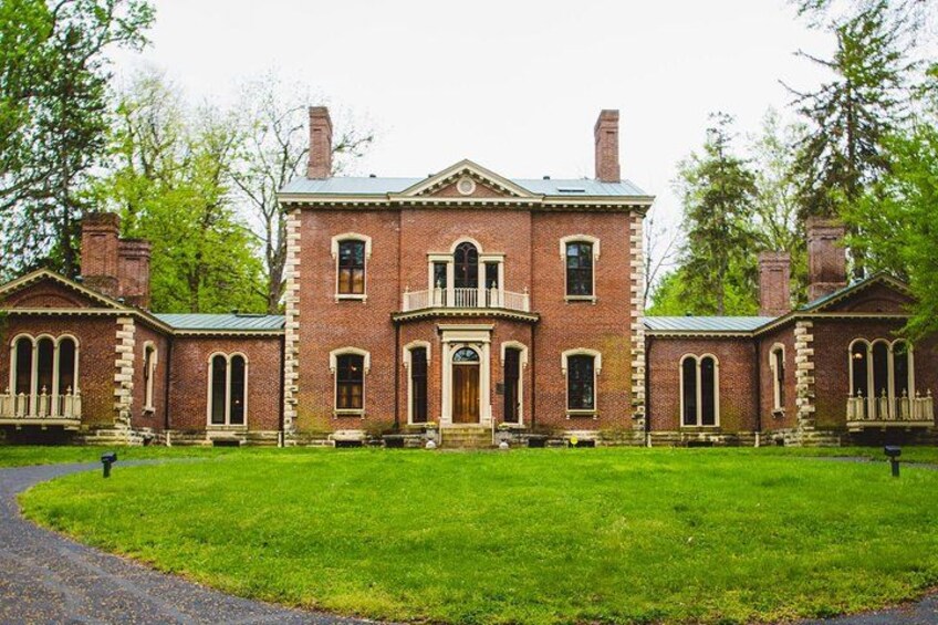 A large brick building with a central entrance, surrounded by a well-maintained lawn and trees. 1