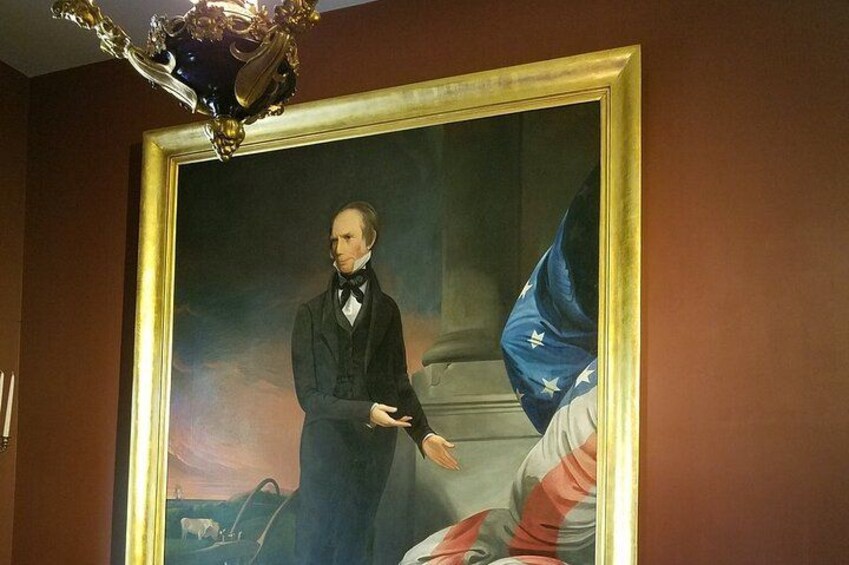 A portrait of a man in formal attire, a chandelier, and a flag. 4